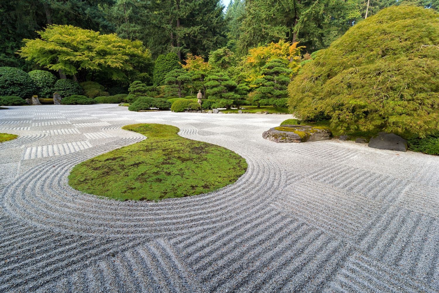 Traditional Japanese Zen Garden with raked sand patterns and moss islands